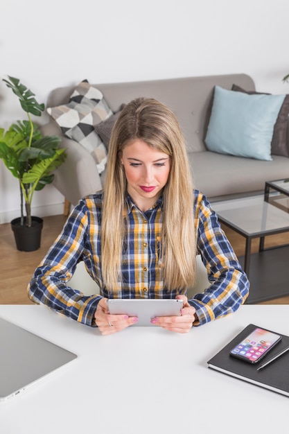 Young woman looking at digital tablet at desk in home interior 