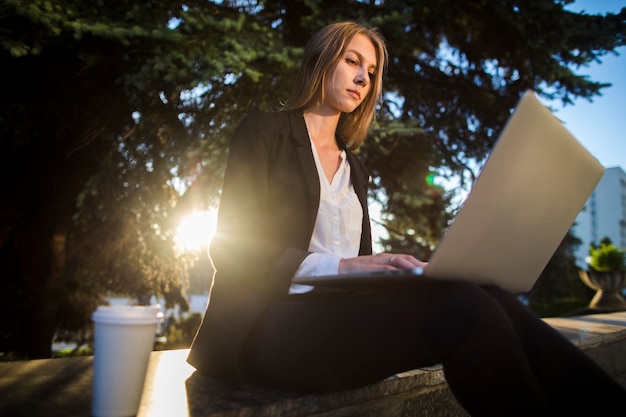 Free photo young woman looking at her laptop low angle shot