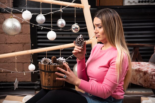 Young woman looking at pinecone at home.