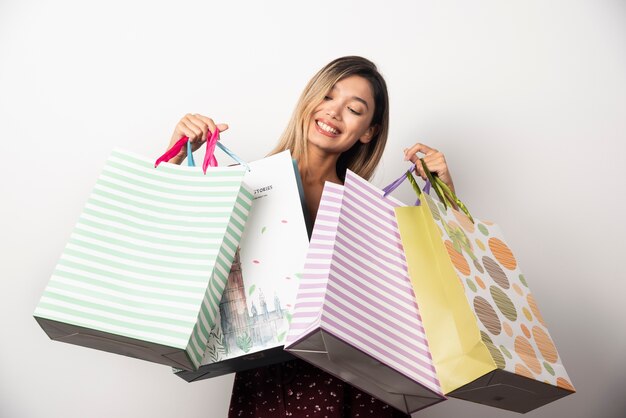 Young woman looking on shop bags on white wall. 