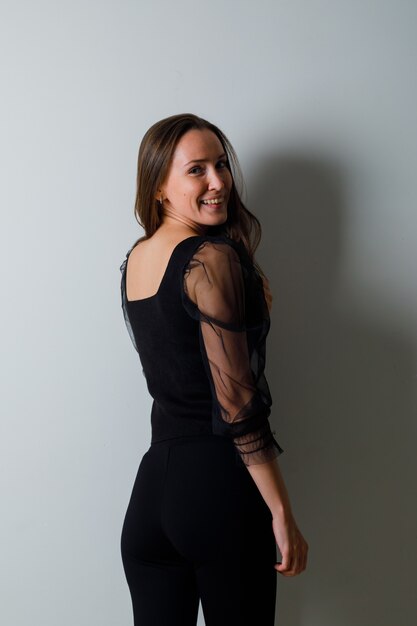 Young woman looking over shoulder in black blouse and black pants and looking attractive