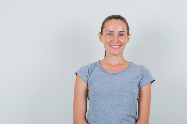 Free Photo young woman looking and smiling in grey t-shirt , front view.