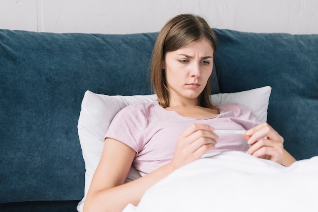 Young woman looking at thermometer