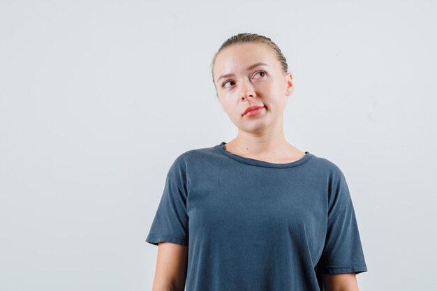 Young woman looking up in gray t-shirt and looking dreamy