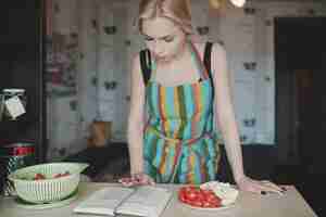 Free photo young woman looking up in a recipes book