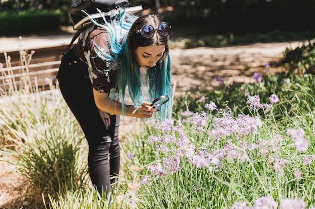 Free photo young woman looking wild flowers through magnifying glass