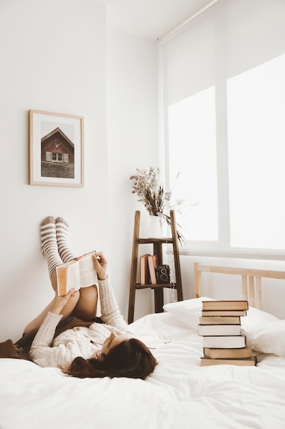 Free photo young woman lying on bed with book