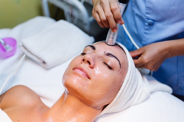 Young woman lying on cosmetologist's table during rejuvenation procedure