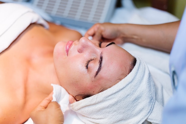 Free Photo young woman lying on cosmetologist's table during rejuvenation procedure