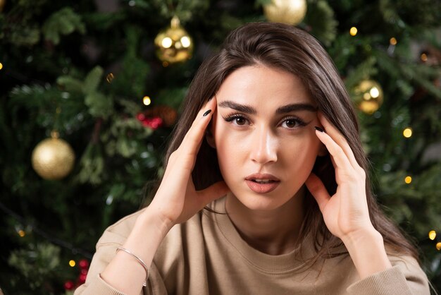 Young woman lying down on fluffy carpet near Christmas tree .