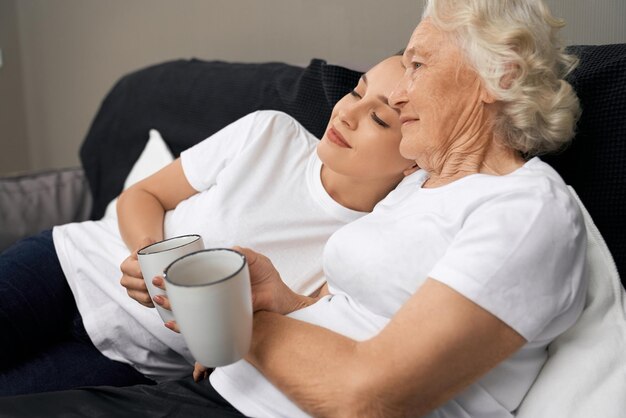 Young woman lying on shoulder of grandmother