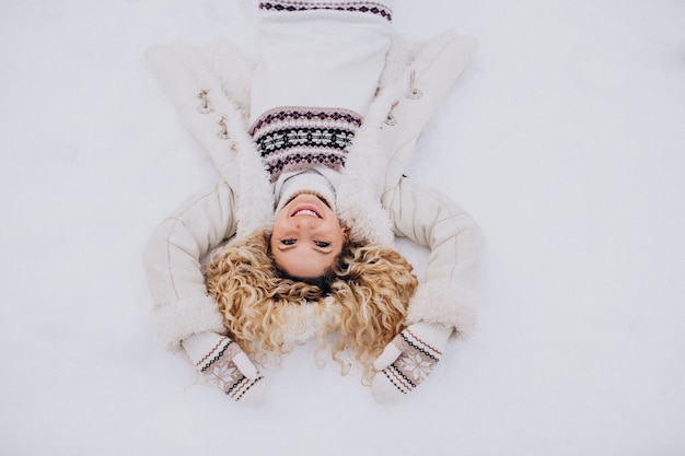 Free photo young woman lying on snow in park