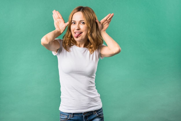 Free photo young woman making funny gesture standing against green background