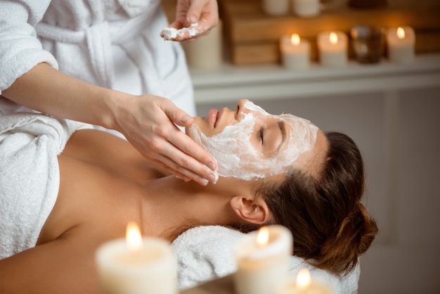 Young woman in mask for face relaxing in spa salon.