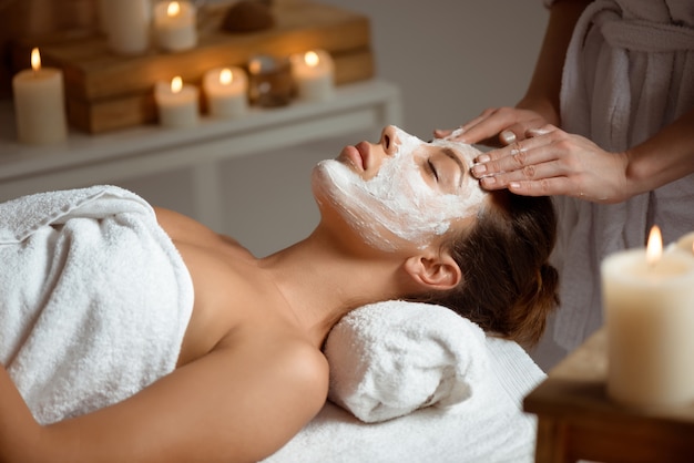 Young woman in mask for face relaxing in spa salon.