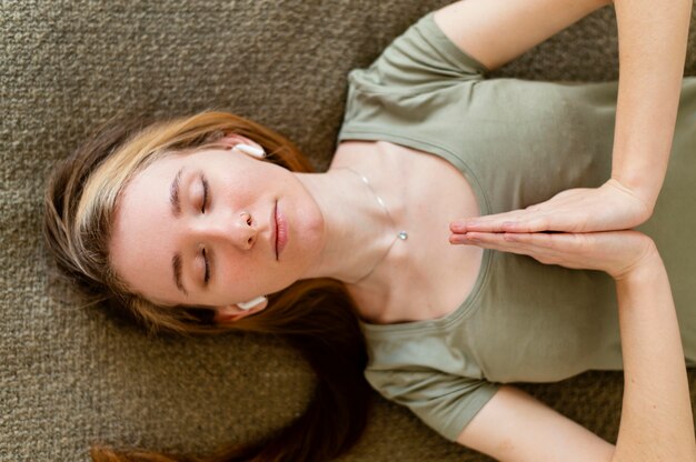 Young woman meditating at home laid on floor