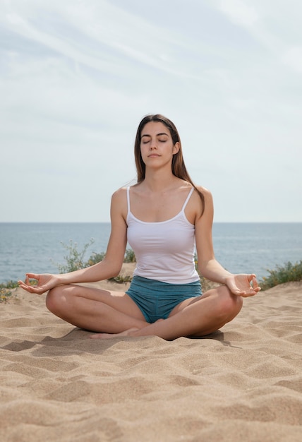 Young woman meditating on sand