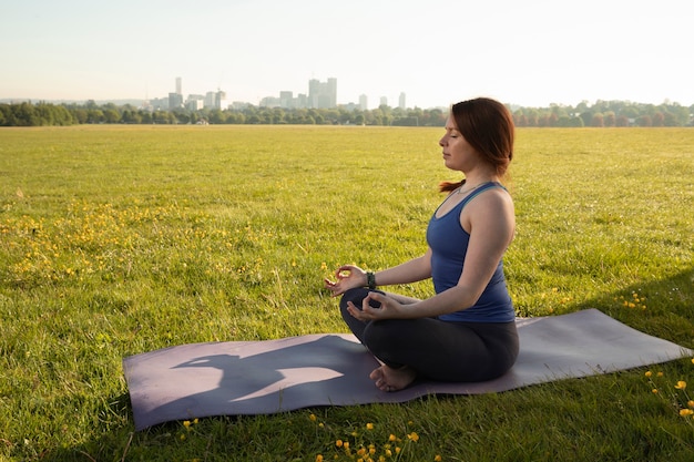 Free photo young woman meditating on yoga mat outdoors