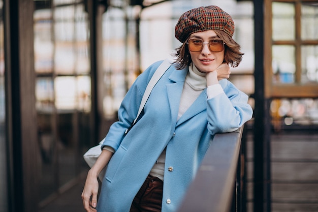 Free Photo young woman model in blue coat by the cafe