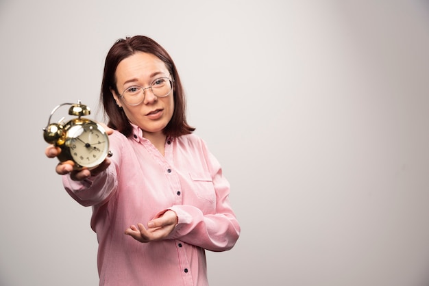 Young woman model holding an alarm clock on a white background. High quality photo