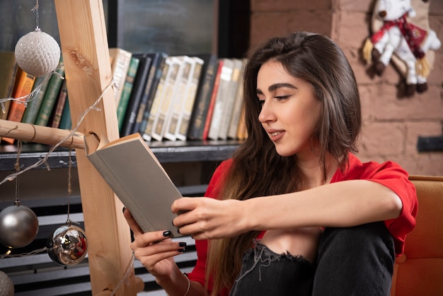 A young woman model sitting and reading a book .