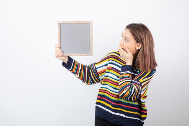 young woman model standing and holding a frame.