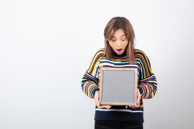 young woman model standing and holding a frame.