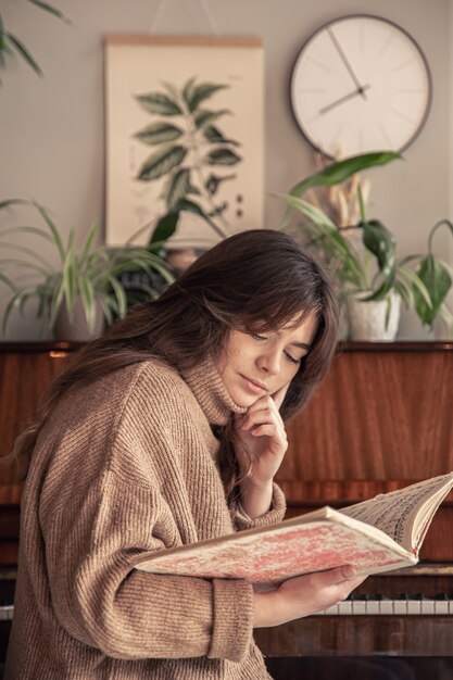 Young woman musician looks into a collection of notes sitting at the piano