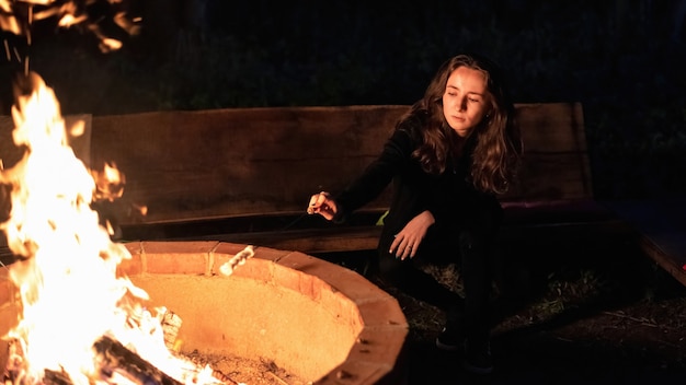 Free Photo young woman near a campfire at glamping, night. frying marshmallow