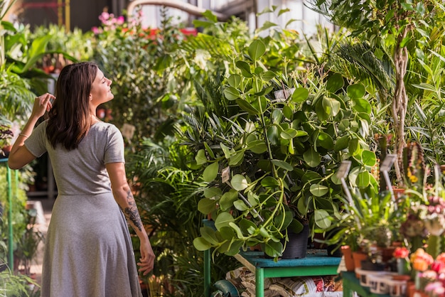 Young woman near green plants in pots