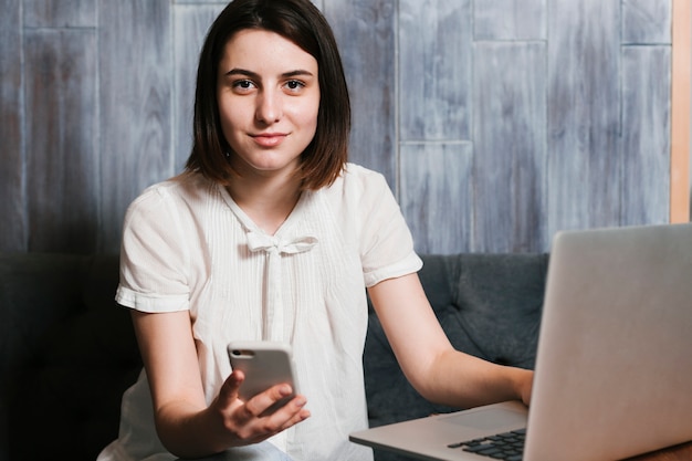 Young woman in the office with laptop and smartphone