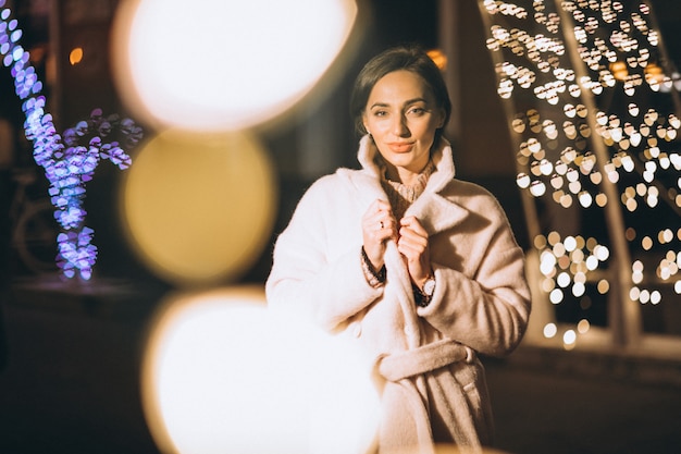 Free photo young woman outside the night street with lights