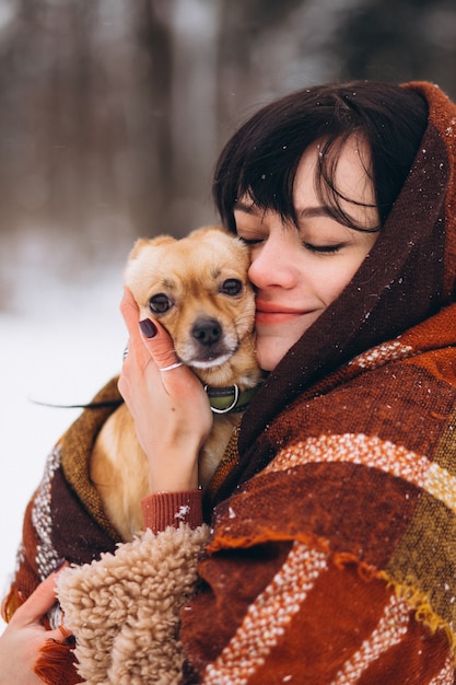 Free Photo young woman outside the park with her little dog at winter