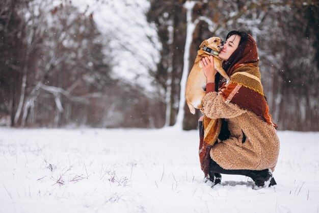 Young woman outside the park with her little dog at winter