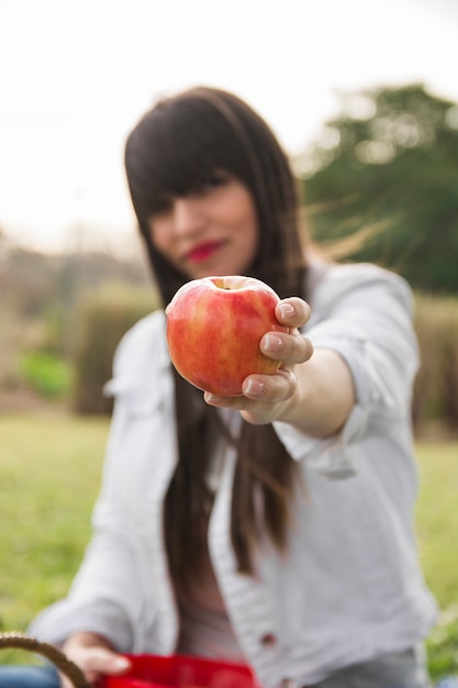 Free photo young woman in park showing red apple