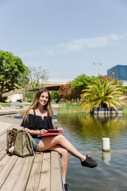 Young woman in park with tablet and book