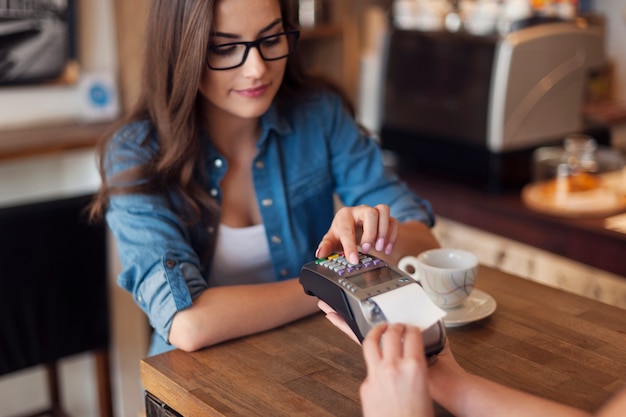 Free Photo young woman paying for cafe by credit card reader