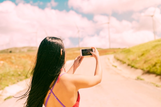 Free photo young woman photographing landscape on phone