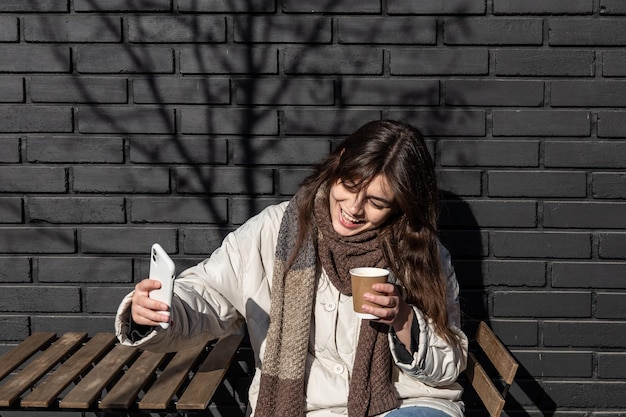 A young woman photographs a glass of hot drink on a walk in the city