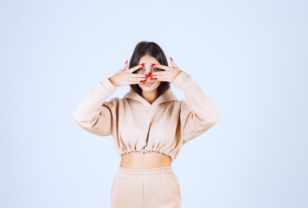 Young woman in a pink hoodie looking across her fingers