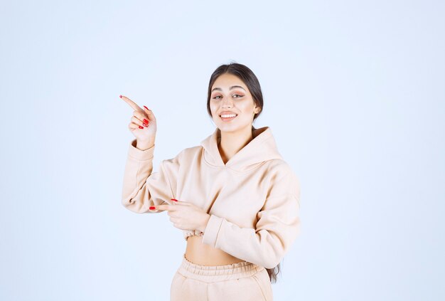 Young woman in a pink hoodie pointing something on the left