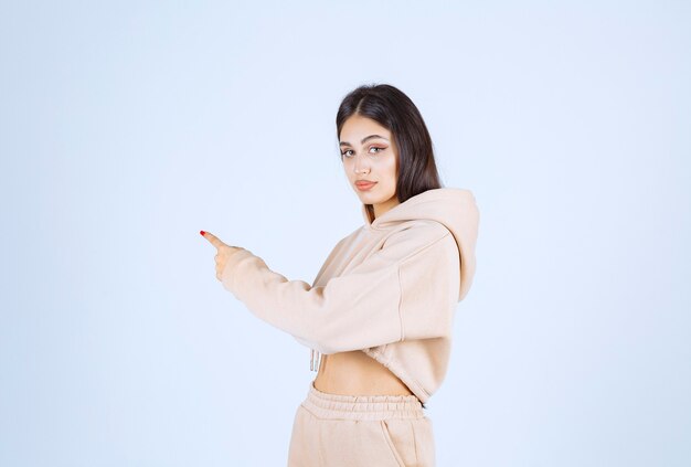 Young woman in a pink hoodie pointing behind