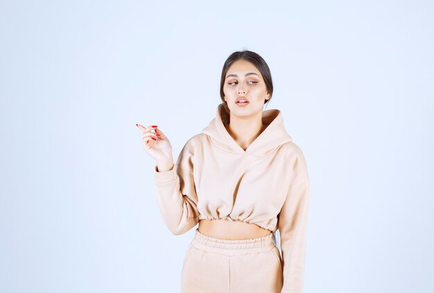 Young woman in a pink hoodie pointing behind