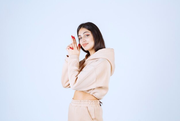 Young woman in a pink hoodie showing gun sign