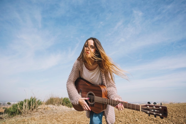 Free Photo young woman playing guitar in nature