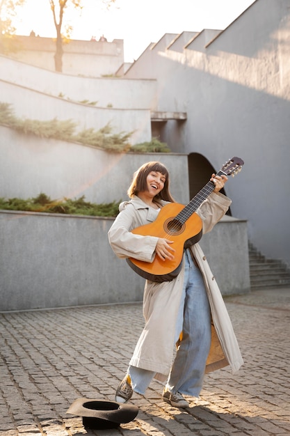 Free photo young woman playing guitar outdoors