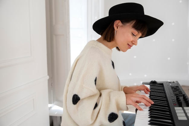 Free photo young woman playing the piano indoors