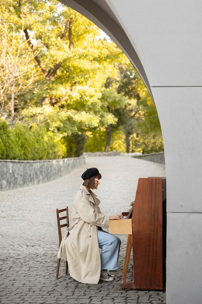 Free photo young woman playing the piano outdoors with copy space