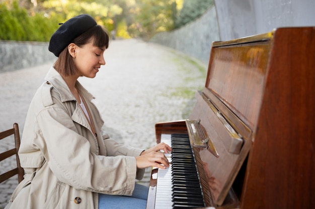 Free photo young woman playing the piano outdoors