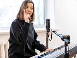 Free photo young woman playing piano sitting in front of microphone